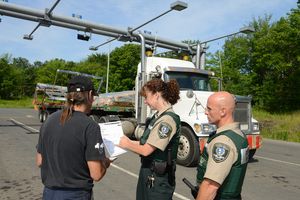 Photo de deux contrôleurs routiers présentant un rapport à un camionneur.