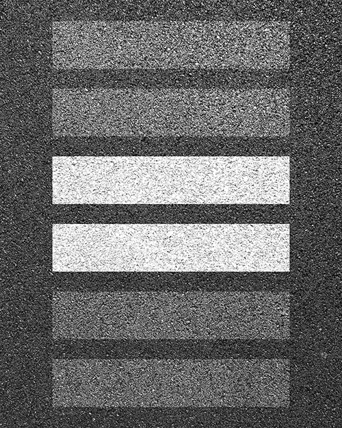 L’image représente une vue aérienne d’un passage pour piétons sur lequel deux des lignes sont mises en évidence afin de représenter le signe égal (=). Par cette image, on veut passer le message que la route doit se partager également entre tous les usagers.